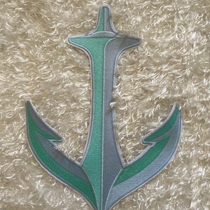 May include: A green and gray embroidered anchor patch. The anchor is stylized to look like the Space Needle in Seattle.
