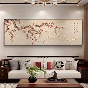 Puede incluir: Una obra de arte mural rectangular que representa una rama con flores rosas y pequeños peces naranjas nadando debajo. La obra tiene un fondo neutro y está enmarcada en negro. El estilo recuerda al arte asiático tradicional.