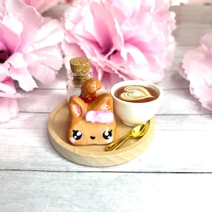 May include: A white ceramic mug with a black handle and the text "But First, Coffee" in a bold, black font. The mug is on a wooden surface. The mug is 10 cm tall.