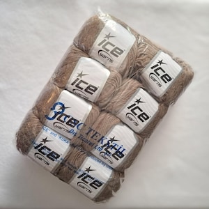 May include: A pack of eight light brown yarn balls wrapped in clear plastic. Each ball features a white label with the black text "ice yarns" and a star logo. The packaging includes additional printed text "ICE TEKSTIL" and company details.