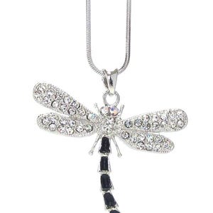 May include: Silver-toned dragonfly pendant necklace. The dragonfly features crystal-like accents on its wings and body, with black segments on the tail. The necklace has a delicate chain.