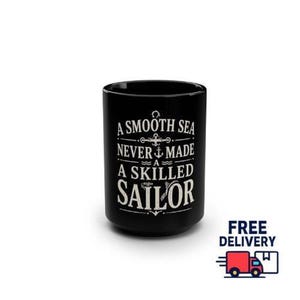 May include: A black ceramic mug featuring white printed text that reads A SMOOTH SEA NEVER MADE A SKILLED SAILOR, accompanied by a small anchor graphic centred between the lines of text, set against a plain white background.