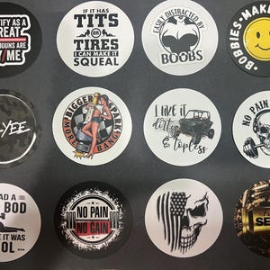 May include: A collection of round stickers with various designs and text. Some stickers feature phrases like "I identify as a threat," "If it has tits or tires I can make it squeal," and "I like it dirty & topless." Other stickers have images of a skull, a woman, and a smiley face.