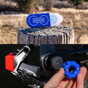 May include: A blue and white CR2032 battery holder with a CR2032 battery. The image also shows a red and black bicycle component and a blue tool being held near a black bicycle component.