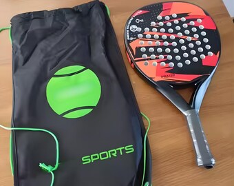 May include: A black padel racket with a red and orange design, next to a black drawstring bag with a green tennis ball graphic and the word "SPORTS". The racket has the text "PRA190".