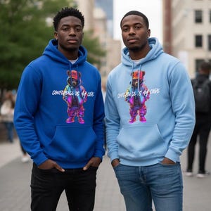 Op de afbeelding: Twee mensen dragen blauwe hoodies met een berenafbeelding en de tekst "CONFIDENCE IS MY CODE". De hoodies hebben een voorzak en een capuchon met trekkoord. Eén hoodie is koningsblauw, de andere lichtblauw. De berenafbeelding is kleurrijk.