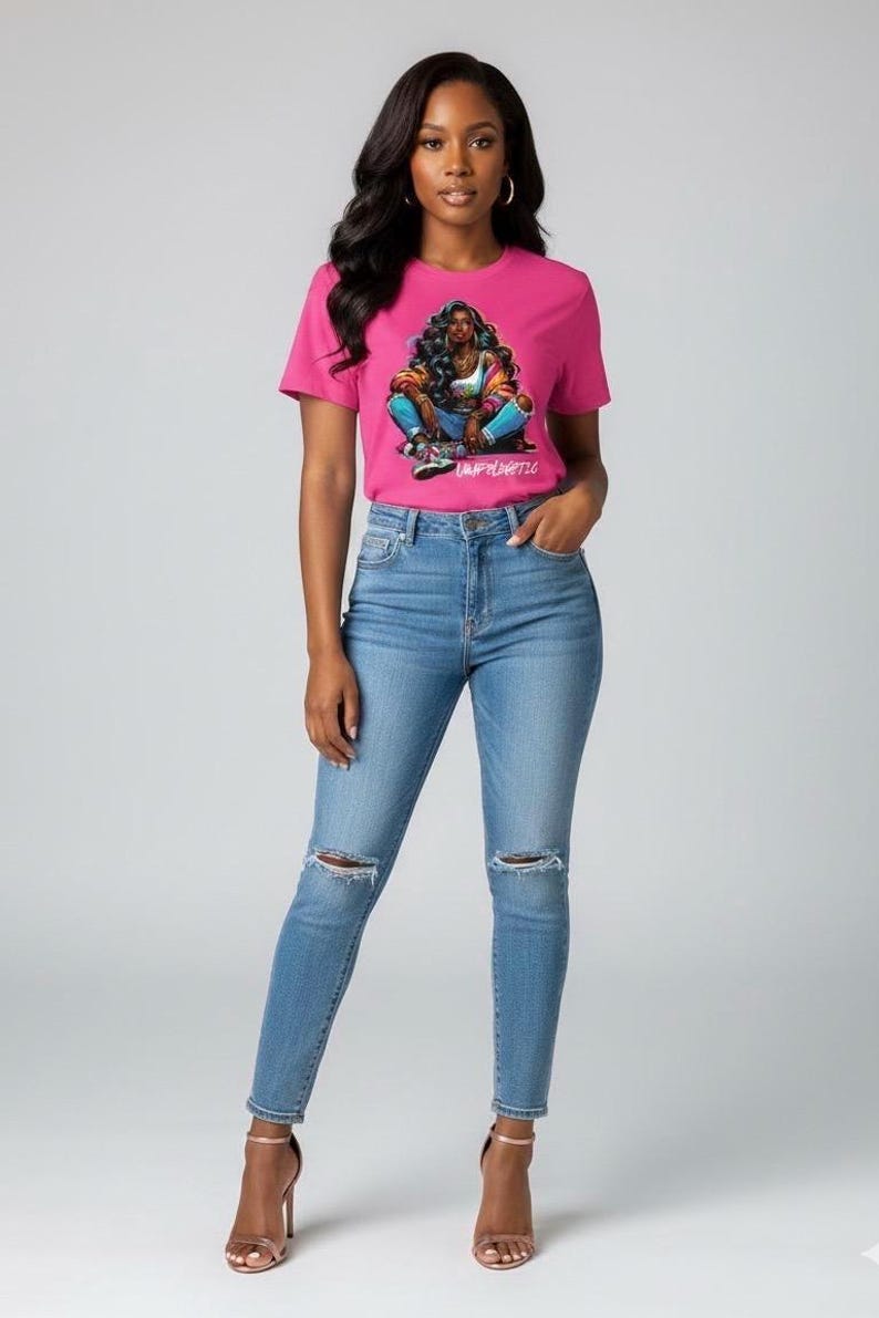 Op de afbeelding: Een vrouw draagt een roze t-shirt met een grafisch ontwerp en lichtblauwe jeans met gescheurde knie&euml;n. Het t-shirt heeft een kleurrijke illustratie en het woord "Unfiltered". Ze draagt ook sandalen met hoge hakken.