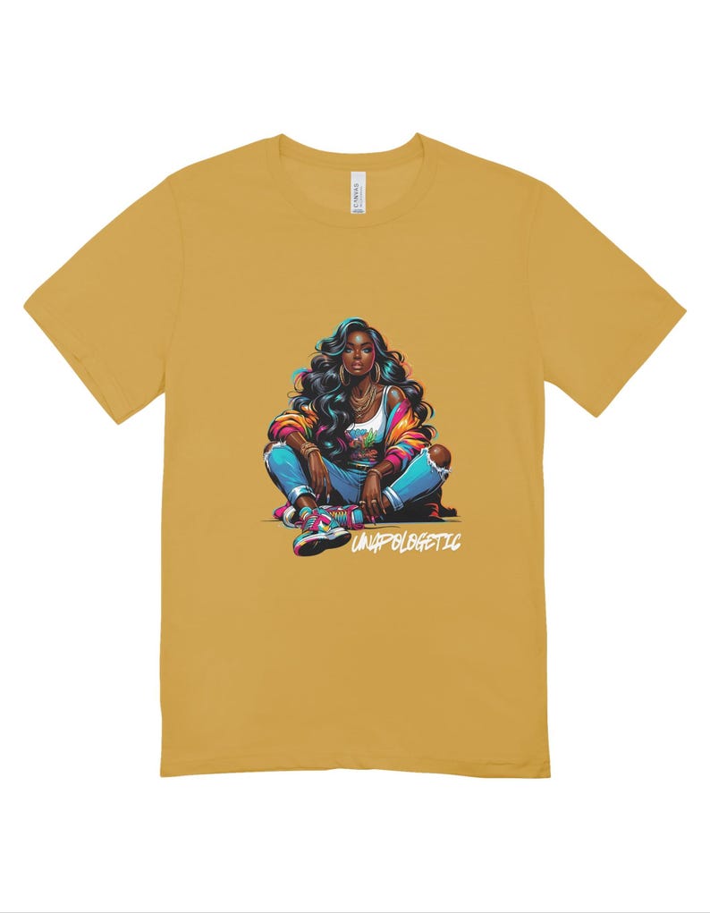 Op de afbeelding: Mosterdgeel T-shirt met een kleurrijke illustratie van een persoon met donker haar, een jas, jeans en sneakers. De tekst "UNAPOLOGETIC" staat eronder. Het shirt is gemaakt van een zacht materiaal.