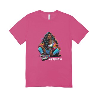 Op de afbeelding: Een magenta t-shirt met een kleurrijke illustratie van een vrouw met donker haar, gekleed in een jas, jeans en sneakers. De tekst "UNAPOLOGETIC" is in het wit gedrukt.