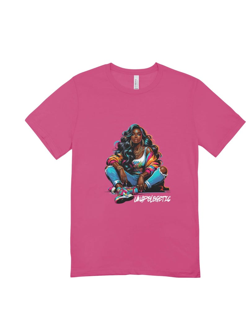 Op de afbeelding: Een magenta t-shirt met een kleurrijke illustratie van een vrouw met donker haar, gekleed in een jas, jeans en sneakers. De tekst "UNAPOLOGETIC" is in het wit gedrukt.
