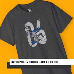 Op de afbeelding: Donkergrijs t-shirt met een distressed afbeelding van een skeletsurfer met een schop en surfboard, tegen de cijfers "86". Het shirt bevat de tekst "OVERSIZES - 5 COLORS - SIZES L TO 3XL".