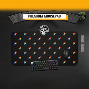 Può includere: Un tappetino per mouse rettangolare nero con un motivo ripetuto di piccoli triangoli multicolori in rosso, giallo, verde e blu. Una grafica bianca di un teschio stilizzato con cuffie è centrata sul bordo superiore del tappetino.
