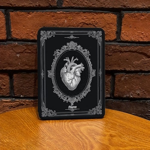 Könnte beinhalten: Eine weiße Keramiktasse mit schwarzem Henkel und dem Text "But First, Coffee" in fetter, schwarzer Schrift. Die Tasse steht auf einer Holzoberfläche. Die Tasse ist etwa 10 cm hoch.