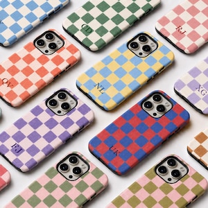 Op de afbeelding: Een collectie smartphonehoesjes met een ruitpatroon in diverse kleurcombinaties. Elk hoesje heeft een uitsparing voor de camera en is gepersonaliseerd met twee letters als initialen, gedrukt in een donker lettertype op het ruitpatroon.