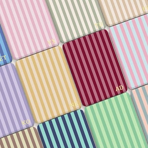 May include: A collection of rectangular cases featuring vertical stripes in various colours including pink, sage green, beige, burgundy, light blue, yellow, lavender, and mint green. Each case displays two gold-coloured letters in the bottom corner.