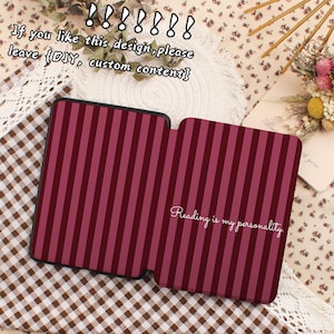 May include: A burgundy and pink striped case, open to reveal the interior. The text "Reading is my personality" is written in cursive. The case is on a patterned surface with text above.