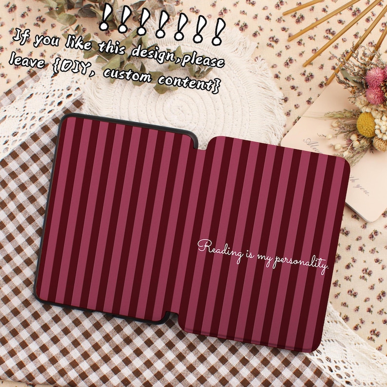 May include: A burgundy and pink striped case, open to reveal the interior. The text "Reading is my personality" is written in cursive. The case is on a patterned surface with text above.