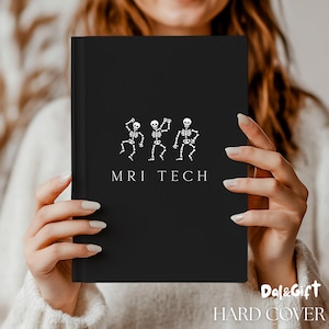May include: Black hard cover notebook with white text and skeleton graphic. The text reads "MRI TECH" below a graphic of three dancing skeletons. The notebook is held by a person wearing a white sweater.