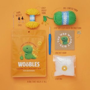May include: An orange background displays a crochet kit for beginners. The kit includes a bag with a green dinosaur, yarn, a crochet hook, stuffing, and step-by-step video instructions. Additional items include a yarn needle and eyes.