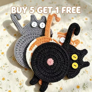 May include: Three crocheted cat-shaped coasters in gray, orange, and black. Each coaster features a circular body, a tail, and two button eyes. The black coaster has a pink center detail. The text BUY 5 GET 1 FREE is visible at the top.