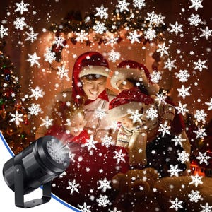 Könnte beinhalten: Ein schwarzer LED-Schneeflockenprojektor beleuchtet eine Familie mit Weihnachtsmützen und schafft eine festliche Winterszene. Weiße Schneeflocken werden auf die Familie und den Hintergrund projiziert und erinnern an das Weihnachtsthema. Die Familie versammelt sich um eine rote Decke.