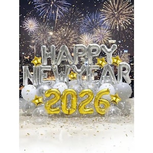 May include: A festive New Year's Eve balloon display. Silver foil balloons spell "HAPPY NEW YEAR" and gold balloons form "2026". Gold star-shaped balloons and confetti add to the celebratory atmosphere, with fireworks in the background.
