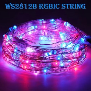 Può includere: Una stringa di luci LED arrotolata con luci rosse, blu e viola. Il testo "WS2812B RGBIC STRING" è visualizzato in alto. Le luci sono avvolte, creando un display vibrante e colorato.