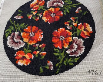 A finished round needlepoint, orange and black flowers