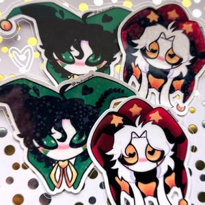 Puede incluir: Cuatro pegatinas con personajes de dibujos animados con sombreros de bufón. Dos pegatinas tienen sombreros verdes y dos tienen sombreros rojos. Los personajes tienen caras blancas, mejillas rosadas y ojos grandes. Las pegatinas están sobre un fondo brillante dorado y blanco.