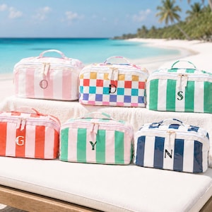 May include: Six rectangular toiletry bags with top handles and zipper closures. The bags feature various patterns including pink and white stripes, a multi-colored checkerboard, green and white stripes, red and white stripes, and blue and white stripes.