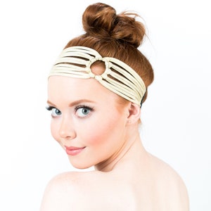 Puede incluir: Una mujer con cabello rojo lleva una diadema blanca con un corte circular. La diadema está hecha de tiras de cuero trenzadas.