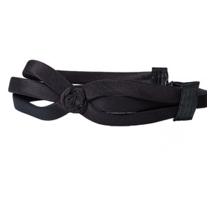 May include: A black headband with a knotted bow detail. The headband is made of a soft, stretchy material and is designed to be comfortable to wear.