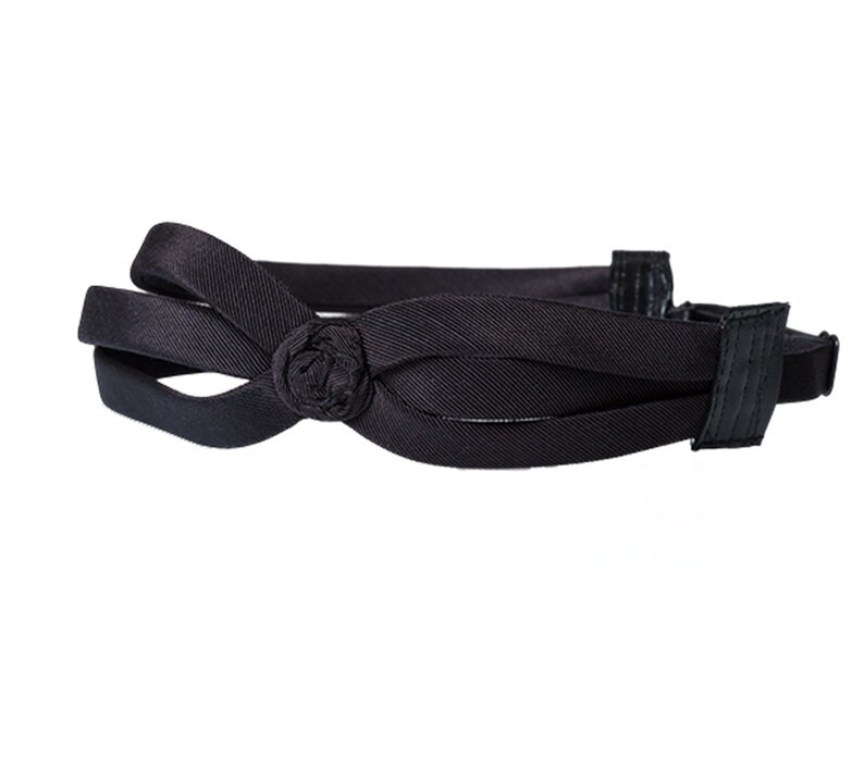 May include: A black headband with a knotted bow detail. The headband is made of a soft, stretchy material and is designed to be comfortable to wear.
