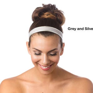 May include: A woman with a bun in her hair is wearing a silver and grey headband. She is looking down and smiling.