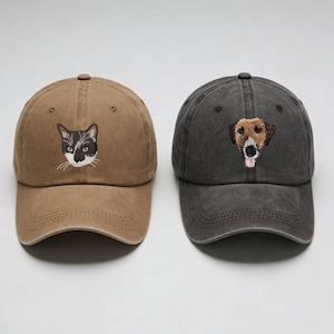 Può includere: Due cappellini da baseball, uno marrone e uno grigio antracite. Il cappellino marrone presenta un volto di gatto ricamato con occhi verdi, mentre il cappellino grigio ha un volto di cane ricamato. Entrambi hanno una visiera curva e un cinturino regolabile.