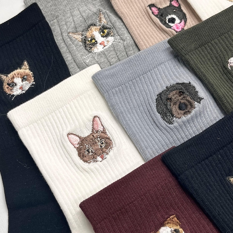 May include: Assorted ribbed socks in various colors, each embroidered with a detailed cat or dog face. The socks are in shades of black, white, gray, and burgundy, with the animal faces in realistic colors. The socks are a cozy and stylish accessory.