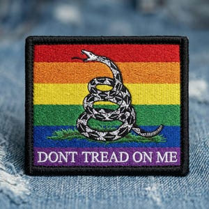 May include: Embroidered patch featuring a coiled rattlesnake over a rainbow-colored background. The patch has the text "DONT TREAD ON ME" in white letters. The patch is square with a black border.