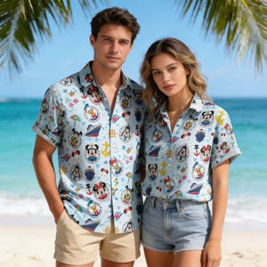 Könnte beinhalten: Hellblaue Hemden mit Knöpfen und einem sich wiederholenden Muster aus Zeichentrickfiguren, Ankern und Schiffen. Die kurzärmeligen Hemden werden von zwei Personen an einem Strand getragen. Der Hintergrund umfasst Palmen, Sand und das Meer.