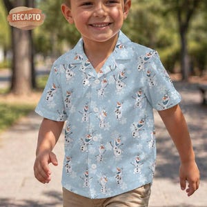 May include: A light blue short-sleeve button-down shirt featuring an all-over print of Olaf the snowman from Frozen, interspersed with white snowflake patterns. The shirt has a classic collar, a front button placket, and a straight hemline.