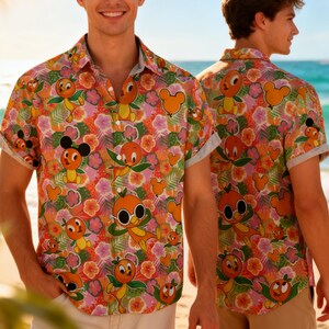 May include: Short-sleeved button-down shirt with a vibrant pattern featuring orange cartoon characters, Mickey Mouse-shaped balloons, and tropical flowers in shades of orange, pink, and green. The shirt has a classic collar and rolled-up sleeves, perfect for a tropical vacation.