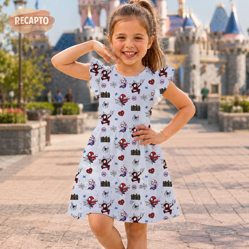 May include: A light blue dress featuring a repeating pattern of Spider-Man, spiderwebs, and hearts. The dress has short, ruffled sleeves and a flared skirt. The background shows a castle and a young girl smiling.