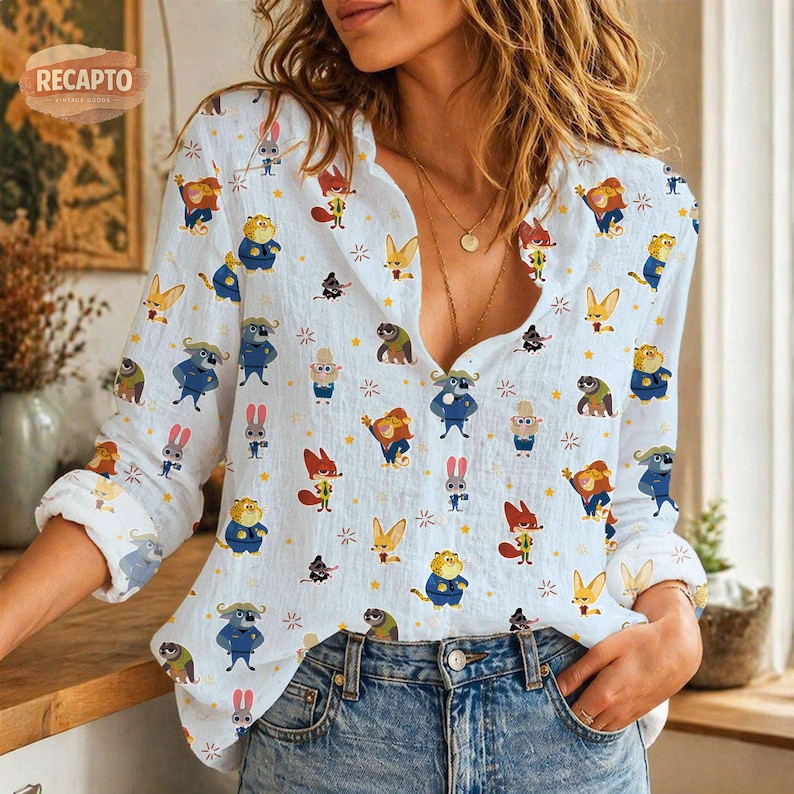 May include: White button-down shirt with a repeating pattern of cartoon animals and stars. The long-sleeved shirt features a collared neckline and is worn with blue jeans. The brand name "RECAPTO" is visible in the upper left corner.