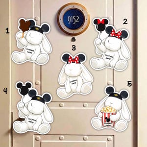 May include: A set of white bunny stickers, each with black Mickey Mouse ears and hats. The stickers feature various items like balloons, popcorn, and a chocolate treat. Each sticker has the text "CUSTOM NAME" printed on it.