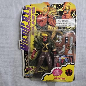 May include: A packaged action figure of "Grifter" from the WildC.A.T.S. comic series. The figure is in a clear plastic case with a yellow and black card. The figure is wearing a green jacket, brown pants, and a red mask. Includes accessories.
