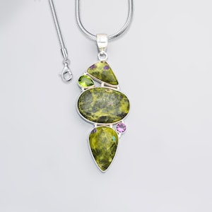 Pode incluir: Um colar de corrente de cobra em prata com um pendente de três grandes pedras verde-azeitona manchadas com inclusões roxas. O pendente é acentuado por uma pequena pedra verde-clara facetada e uma pequena pedra roxa redonda facetada em prata.