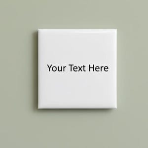 Può includere: Una piastrella quadrata bianca con il testo "Your Text Here" in nero, centrato sulla superficie. La piastrella è posta su uno sfondo verde tenue.