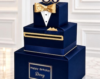 May include: A three-tiered navy blue card box featuring a tuxedo design with a gold bow tie, a white shirt front, and the number 80 on top. The middle tier has a horizontal slot and a pocket square. A label reads Happy Birthday Doug.
