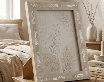 Op de afbeelding: Een rechthoekige fotolijst met een lichte houten afwerking en ingelegde parelmoer accenten. De lijst bevat een botanische print met geschetste bladeren en stelen. De lijst staat op een houten oppervlak.