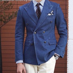 Może przedstawiać: Dwurzędowa dżinsowa marynarka w średnim odcieniu niebieskiego. Marynarka ma złote guziki, klapy z wycięciami i poszetkę. Marynarka jest połączona z koszulą w paski i wzorzystym krawatem. Tekst "GOODCHOICEBySameer" jest widoczny u góry.