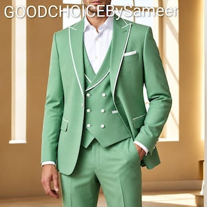 Puede incluir: Un traje de tres piezas en color verde salvia con ribetes blancos en la americana y el chaleco, combinado con una camisa blanca de cuello. El texto GOODCHOICEBySameer es visible arriba. El chaleco cruzado tiene botones blancos.